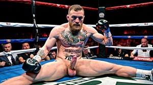 Foto muy realista texturas 8k. Conor McGregor está totalmente desnudo y de cuerpo entero, tiene un pene grande y bonito, tiene testículos grandes y con vello. Está totalmente desnudo de cuerpo entero. Tiene mucho vello en el pecho, piernas y brazos. Está en un gimnasio de boxeo rodeado de hombres boxeadores totalmente desnudos boxeando entre ellos. Amor y pasión.